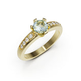 Gold ring with a green gemstone and smaller diamonds on a white background