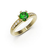 Gold ring with a green gemstone and smaller diamonds on a white background