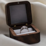 Diamond ring with a diamond in an open wooden box on a light fabric background